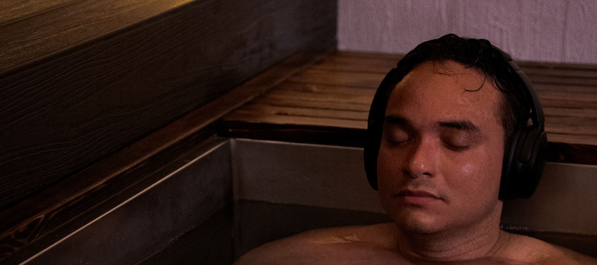 Un hombre sereno dentro del baño de hielo, con audífonos y los ojos cerrados